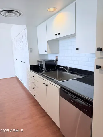 a kitchen with granite countertop white cabinets and black appliances