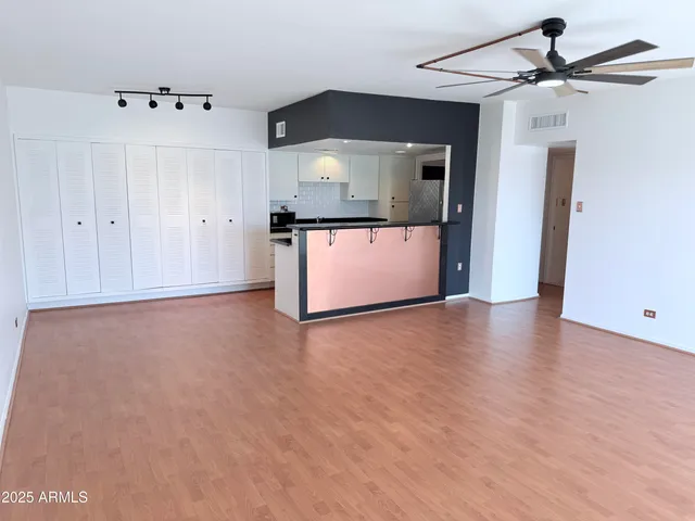a view of a room with a ceiling fan and wooden floor