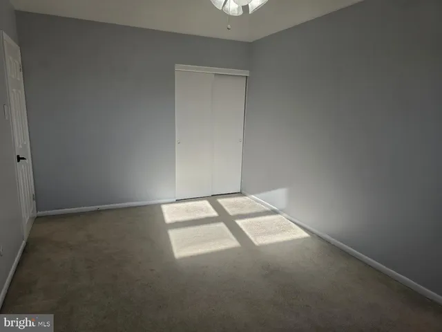 a view of an empty room with a chandelier fan