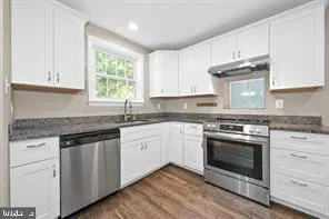 a kitchen with granite countertop stainless steel appliances white cabinets granite counter tops and a hard wood floors