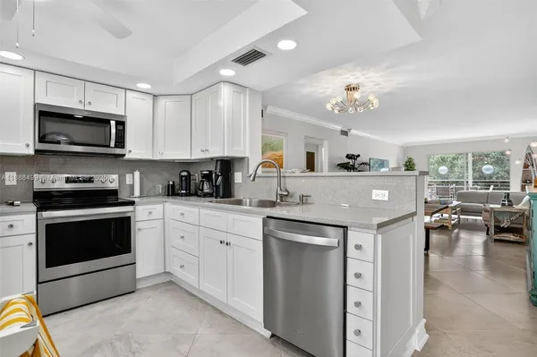 a kitchen with stainless steel appliances granite countertop a stove top oven a sink dishwasher a dining table and chairs with wooden floor