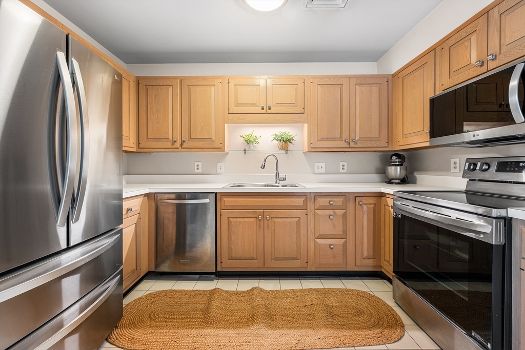 63 Garden Road, Unit C5 Wellesley, MA 02481 - Photo 9 of 30 a kitchen with stainless steel appliances granite countertop a stove a sink and a refrigerator