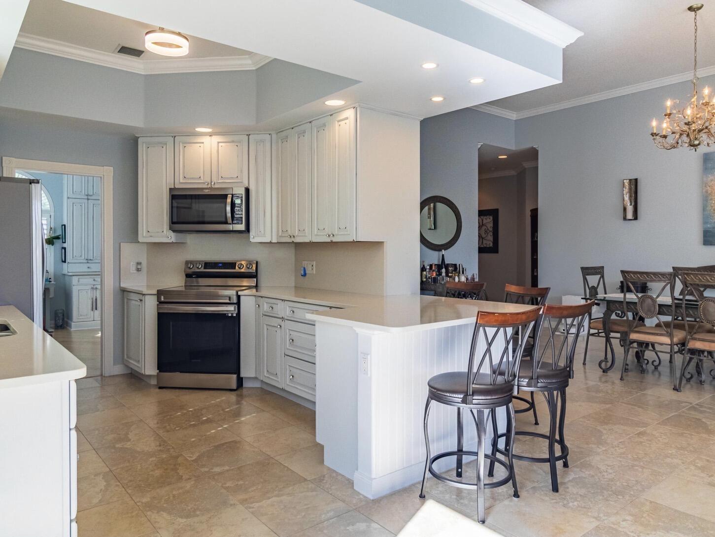 11355 Southwest Rockingham Drive Port St. Lucie, FL 34987 - Photo 9 of 31 a kitchen with stainless steel appliances granite countertop a stove top oven a sink a dining table and chairs