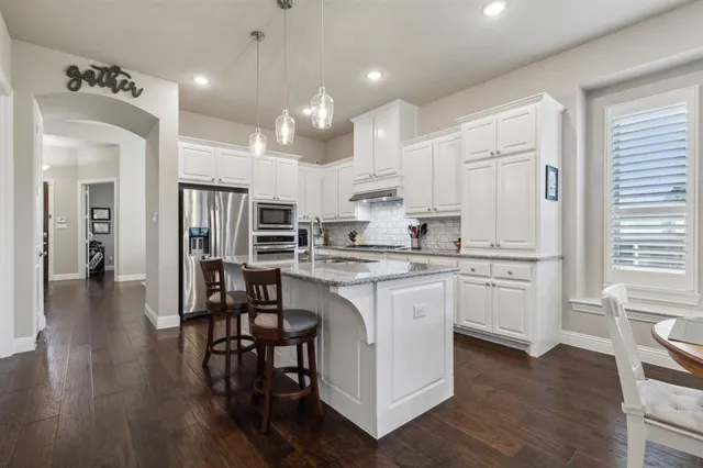 a kitchen with kitchen island granite countertop a sink cabinets and wooden floor