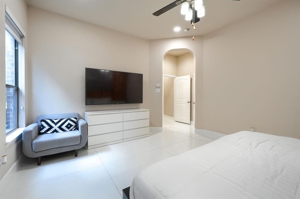 2246 Longview Road Irving, TX 75063 - Photo 20 of 40 Spacious bedroom featuring light-toned walls, white tile flooring, a large window, recessed lighting, and an arched doorway leading to an interior hallway