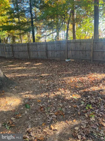 a view of a yard with large trees and wooden fence