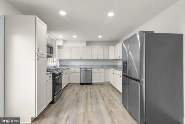 a kitchen with a refrigerator a sink and dishwasher with wooden floor