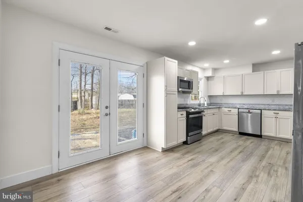 a kitchen with wooden floors and white stainless steel appliances