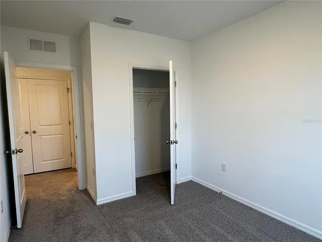 an empty room that has a grey walls and closet