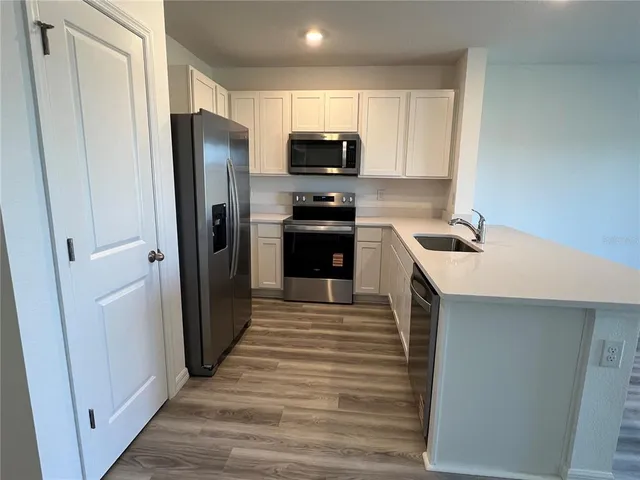 a kitchen with a sink a microwave a refrigerator and cabinets