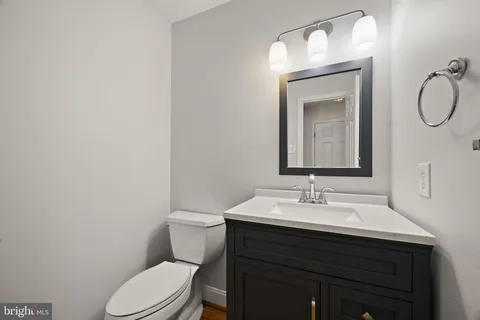 a bathroom with a toilet sink vanity and mirror