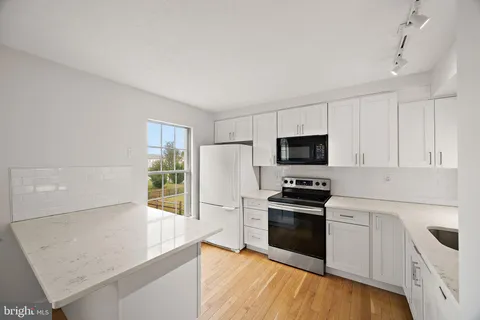 a kitchen with granite countertop white cabinets and stainless steel appliances