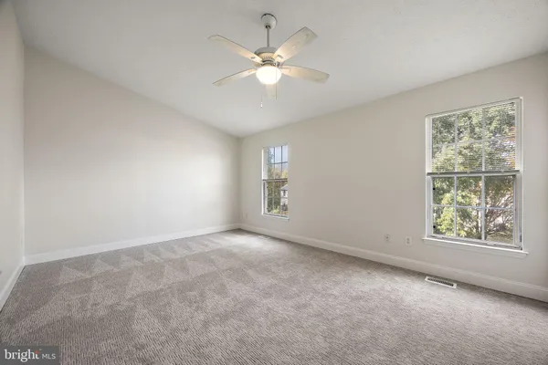 an empty room with windows and chandelier fan