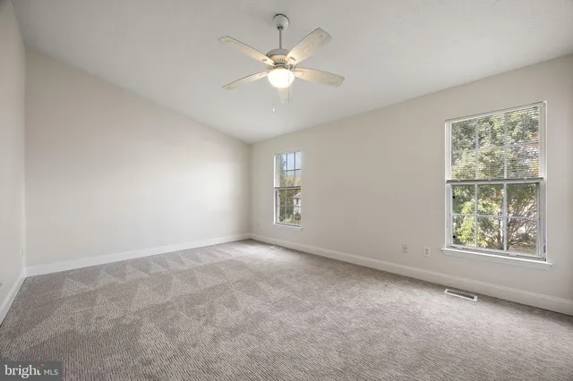 an empty room with windows and chandelier fan