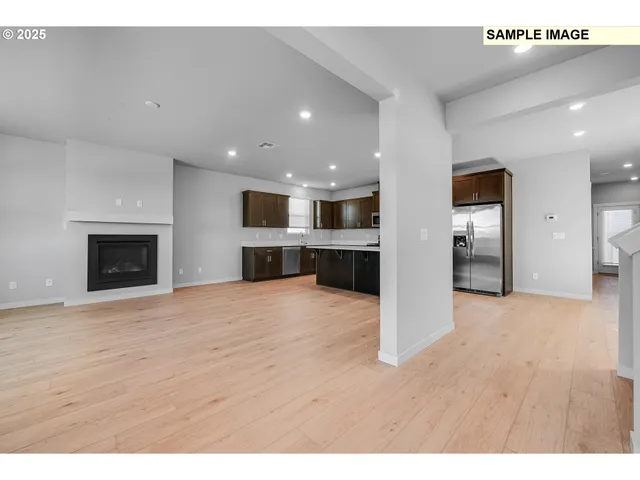 a view of empty room with kitchen and fireplace