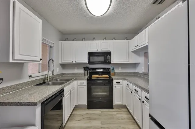 a kitchen with granite countertop a stove sink and cabinets