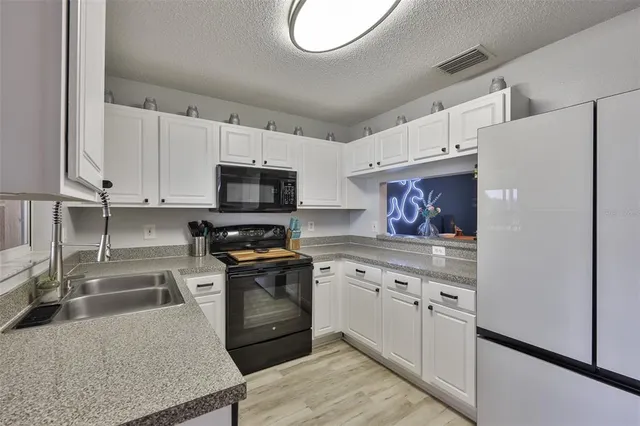 a kitchen with granite countertop a sink stainless steel appliances and cabinets