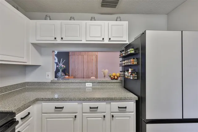 a kitchen with stainless steel appliances granite countertop a refrigerator a sink and white cabinets