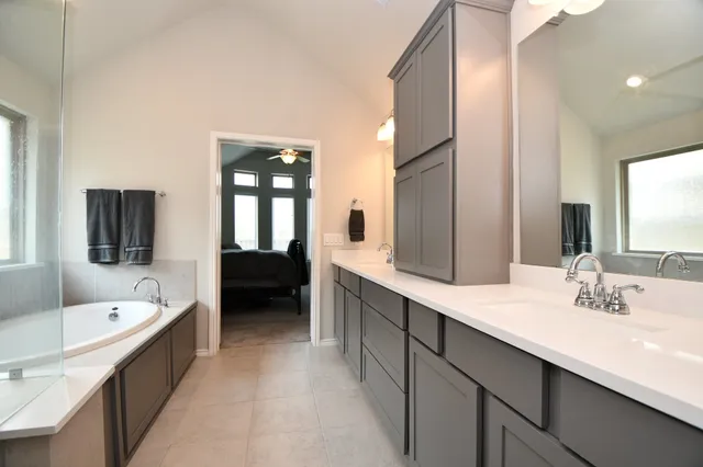 a en suite bathroom with a tub double sink and mirror