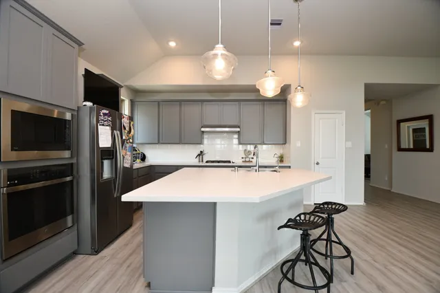 a kitchen with kitchen island a sink stainless steel appliances and wooden floor
