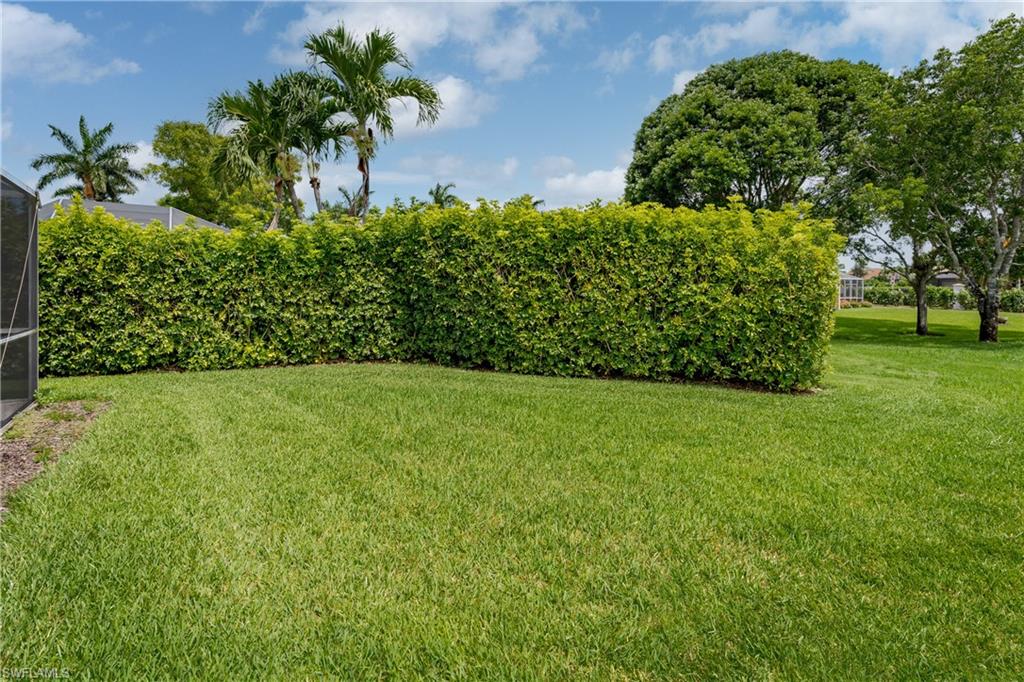 6658 Castlelawn Place, Unit 9 Naples, FL 34113 - Photo 31 of 38 Expansive green lawn bordered by a dense, manicured hedge
