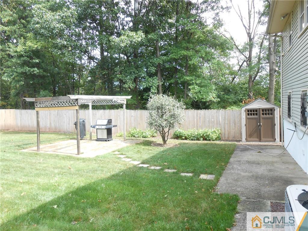 4 Maple Road Iselin, NJ 08830 - Photo 16 of 21 a white house that has a small yard and large trees with wooden fence