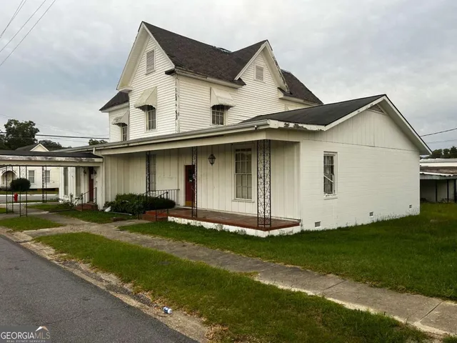 a view of a white house with a big yard and large trees