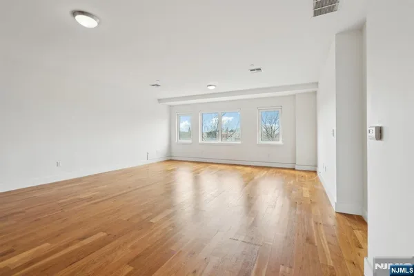 an empty room with wooden floor and windows