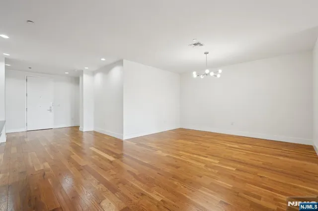 a view of an empty room with wooden floor and a ceiling fan