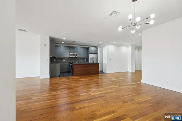 a view of a kitchen with kitchen island a sink wooden floor and a refrigerator