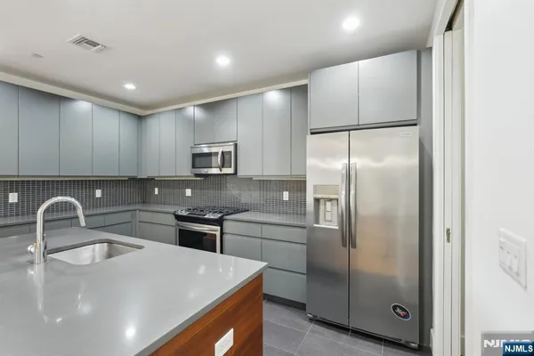 a kitchen with stainless steel appliances granite countertop a sink a stove a refrigerator and island