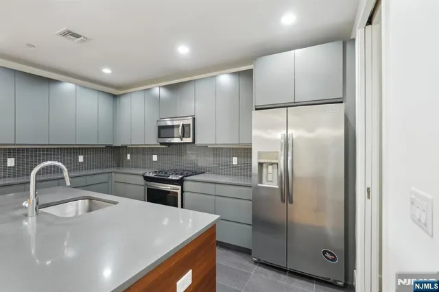 a kitchen with stainless steel appliances granite countertop a sink a stove a refrigerator and island