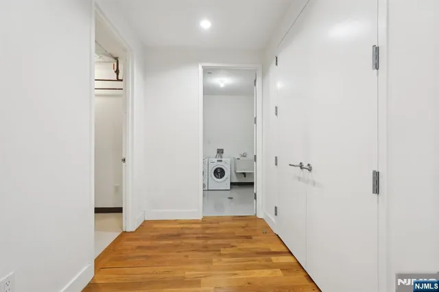 a view of a hallway with wooden floor and a bathroom
