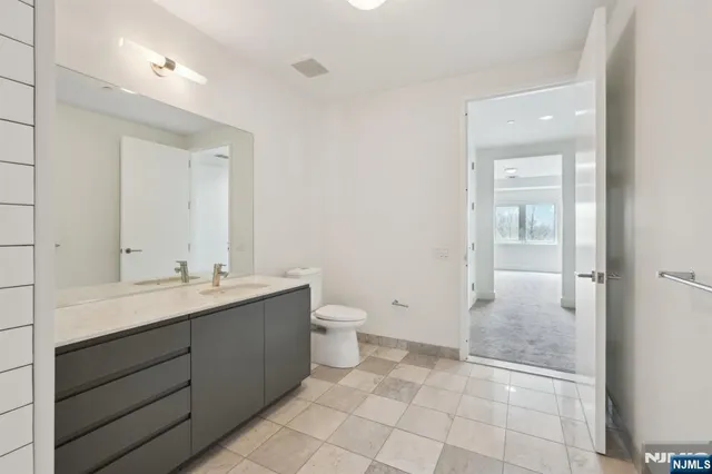 a bathroom with a granite countertop sink a toilet and a mirror