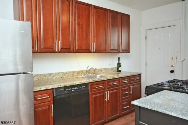 a kitchen with stainless steel appliances granite countertop a sink stove and refrigerator with wooden floor