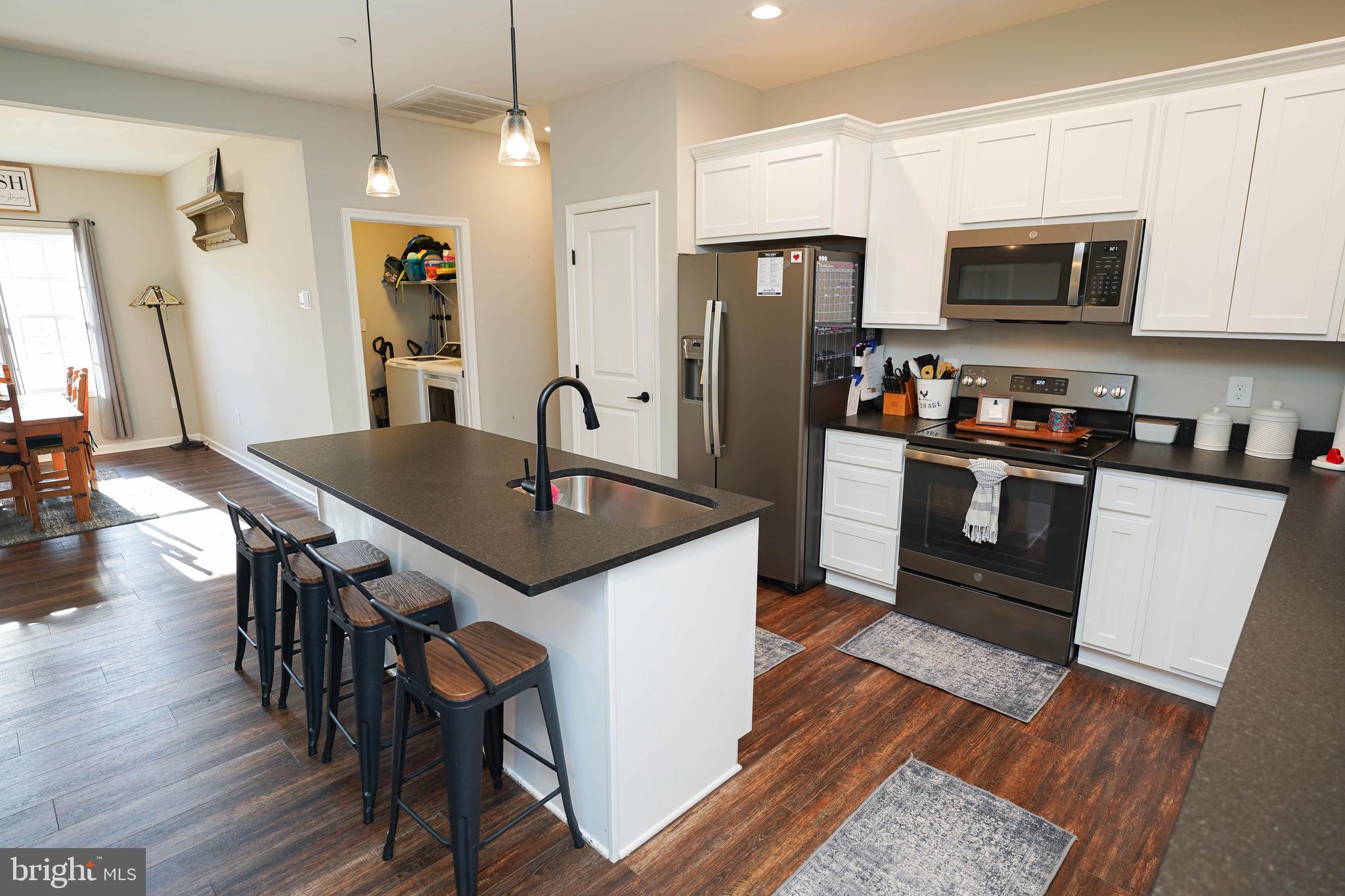 2054 Groton Road Pocomoke City, MD 21851 - Photo 10 of 42 a kitchen with granite countertop a refrigerator a stove a microwave a dining table and chairs with wooden floor