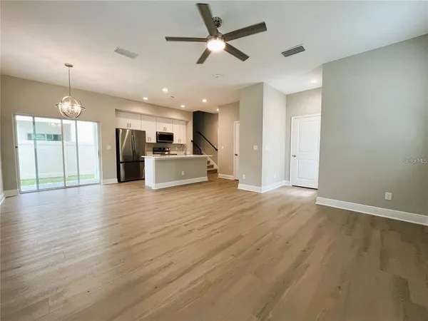 an empty room with wooden floor and a kitchen