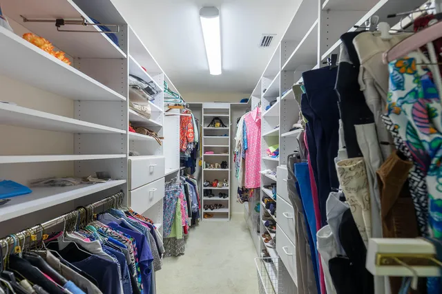 a view of walk in closet with clothes and shoes