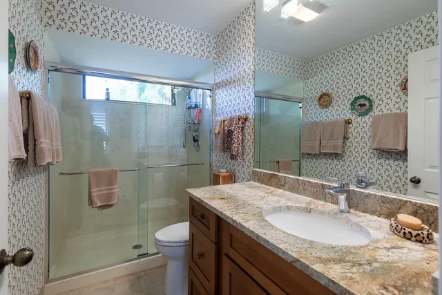 a bathroom with a granite countertop sink a toilet and shower