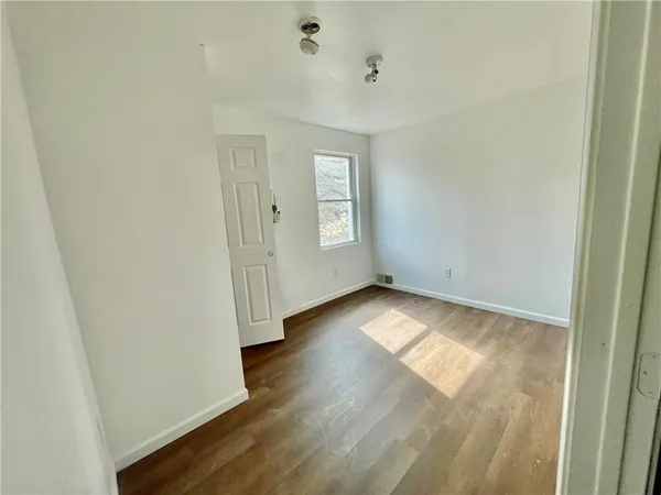 a view of an empty room with closet and windows