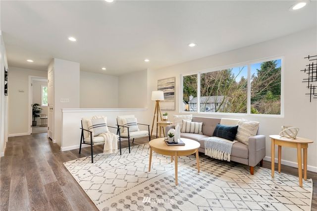a living room with furniture and a large mirror next to a window