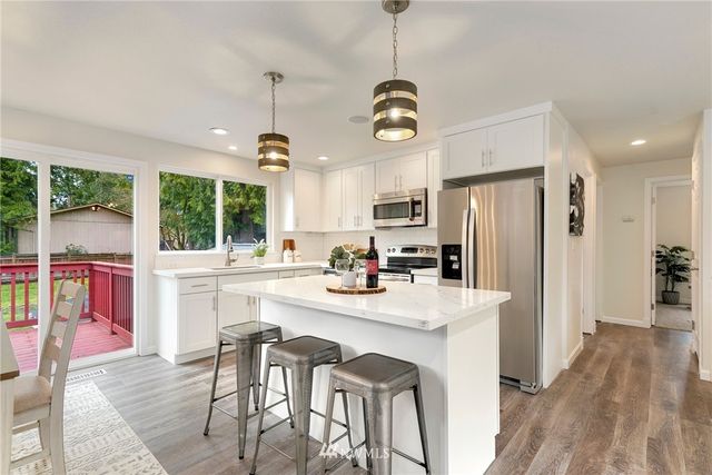 a kitchen with stainless steel appliances kitchen island granite countertop a stove a refrigerator a oven a sink with a dining table and chairs