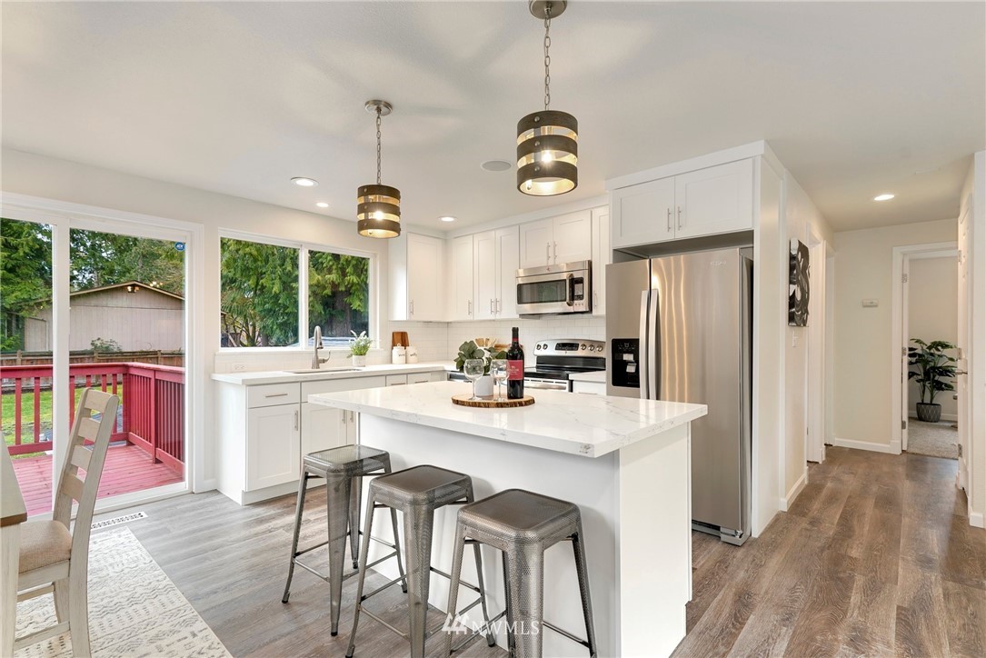17307 18th Avenue Southeast Bothell, WA 98012 - Photo 7 of 40 a kitchen with stainless steel appliances kitchen island granite countertop a stove a refrigerator a oven a sink with a dining table and chairs