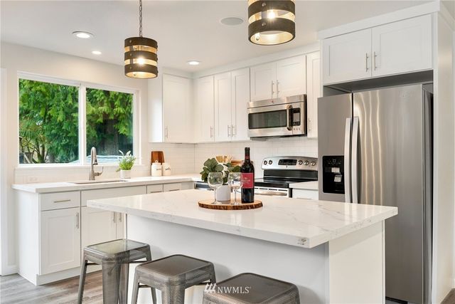 a kitchen with stainless steel appliances kitchen island granite countertop a refrigerator and a stove top oven