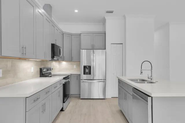 a kitchen with stainless steel appliances a sink stove refrigerator and cabinets