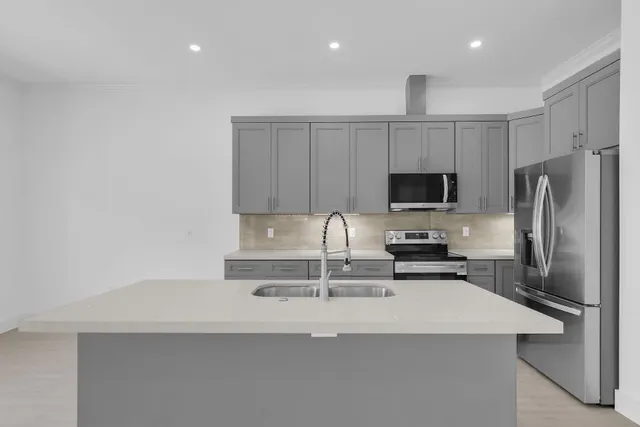 a kitchen with kitchen island a sink stainless steel appliances and cabinets