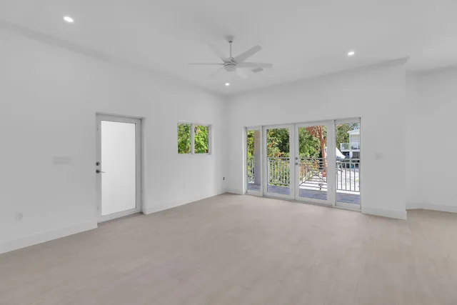 an empty room with windows and ceiling fan