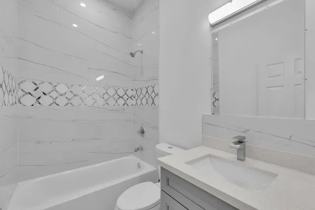 a bathroom with a granite countertop sink a toilet and bathtub