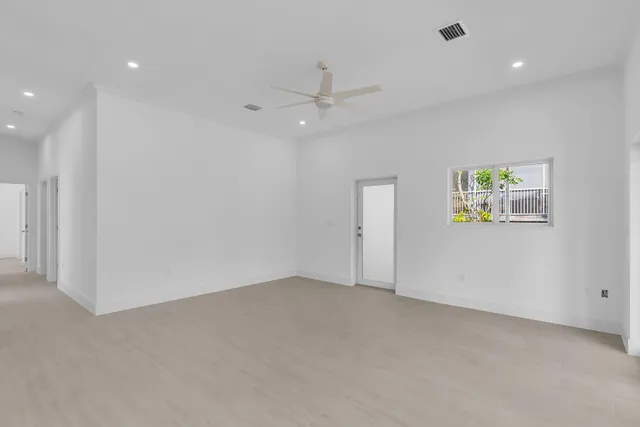 an empty room with windows and ceiling fan