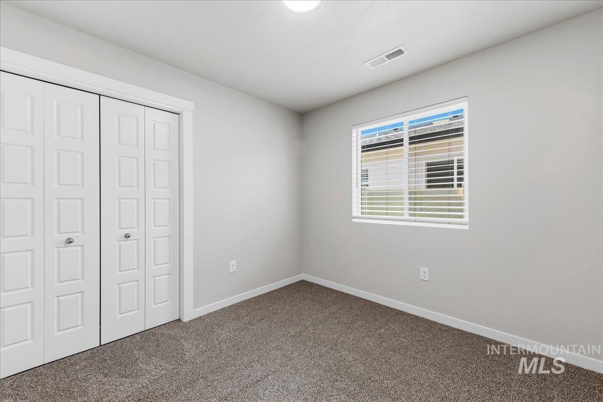 3091 S Green Boise, ID 83709 - Photo 17 of 27 Bedroom featuring bi-fold closet doors, a single window with blinds, light gray walls, white trim, and gray carpet flooring